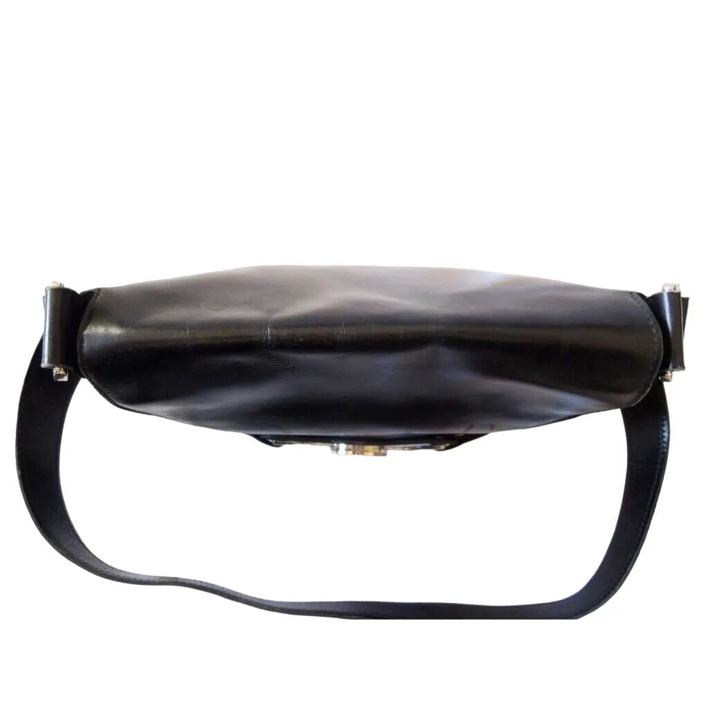 1970s Gucci saddle bag in black leather with muted gold hardware, an expandable bottom, wide shoulder strap, and burgundy leather lining