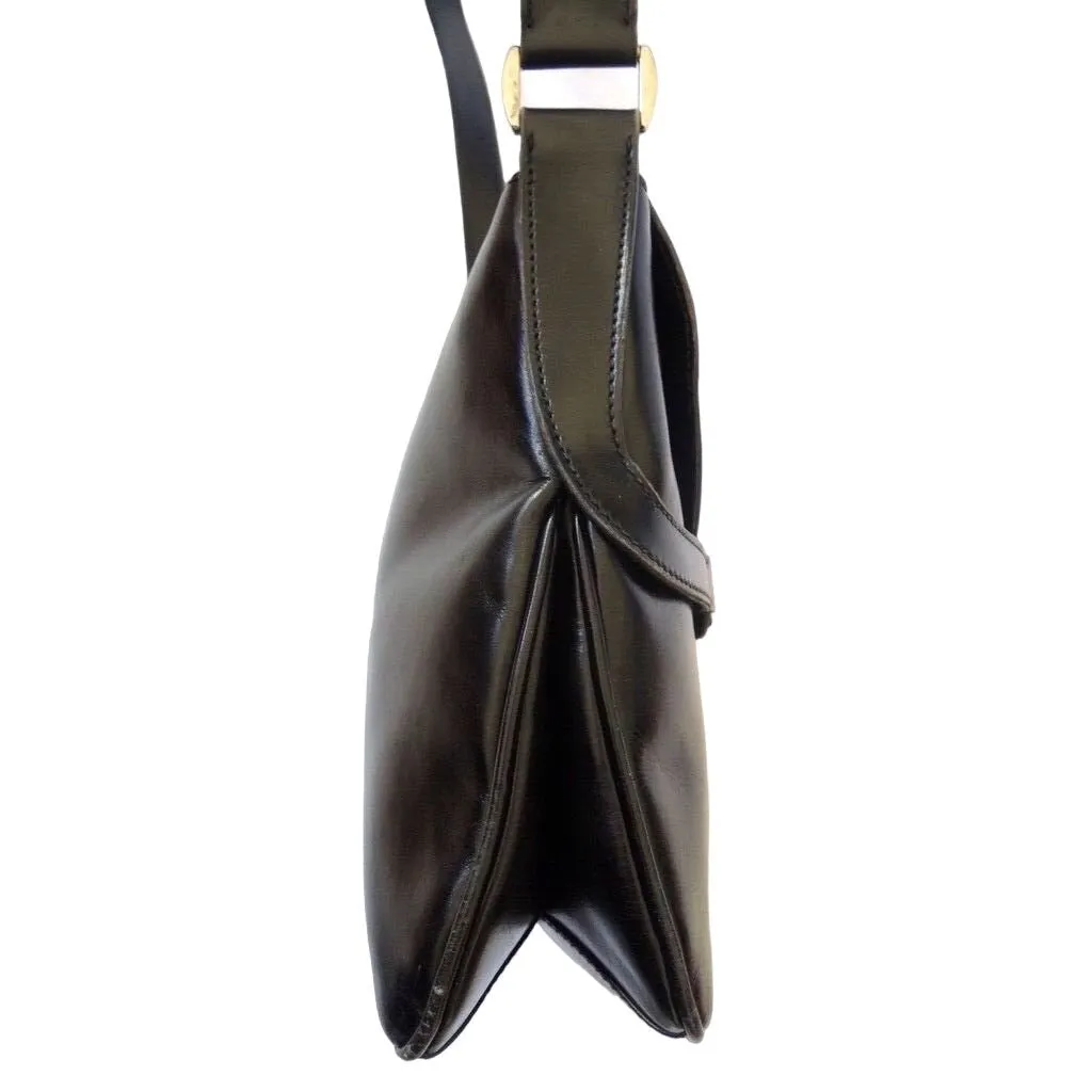 1970s Gucci saddle bag in black leather with muted gold hardware, an expandable bottom, wide shoulder strap, and burgundy leather lining