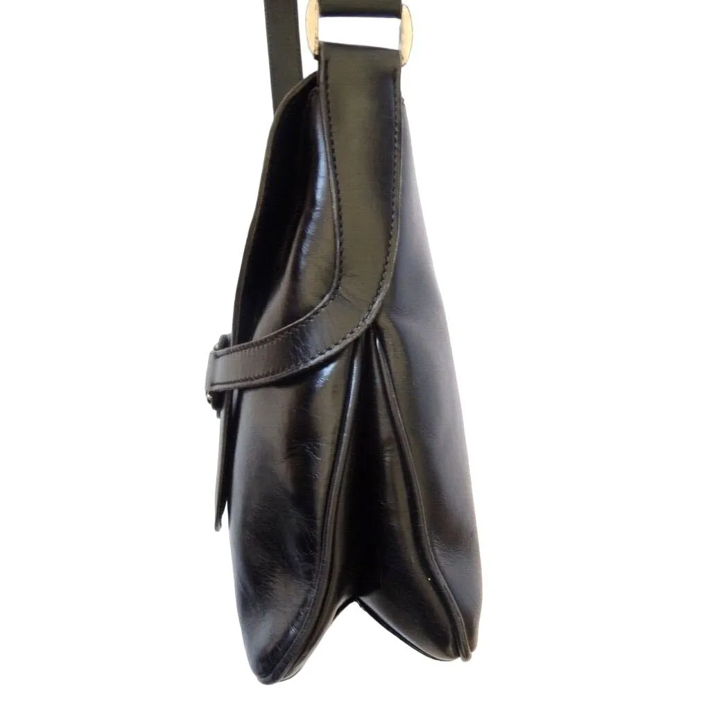 1970s Gucci saddle bag in black leather with muted gold hardware, an expandable bottom, wide shoulder strap, and burgundy leather lining