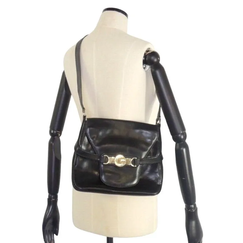 1970s Gucci saddle bag in black leather with muted gold hardware, an expandable bottom, wide shoulder strap, and burgundy leather lining